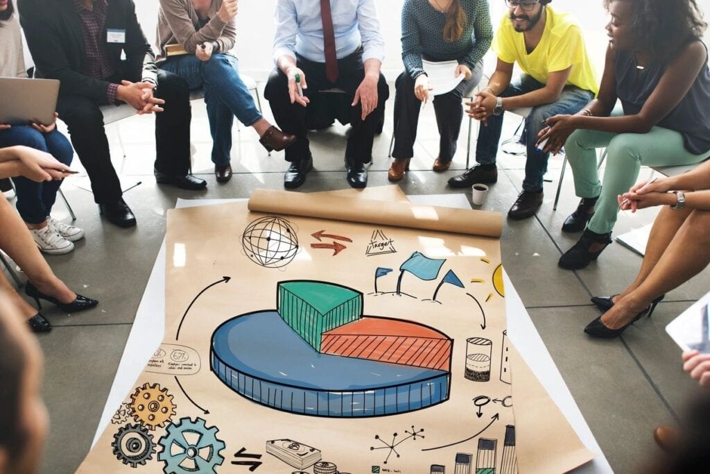 A group discussing a colorful pie chart on paper.